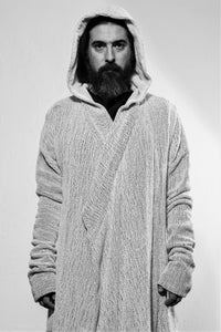 Front with hood up. A white draped cardigan in unregular grid optic with a crossing front. The cardigan is made in Berlin Germany    Colour: overgarment: white              lining: black, white Material: overgarment 100% cotton                lining               80% wool, 20% linen 